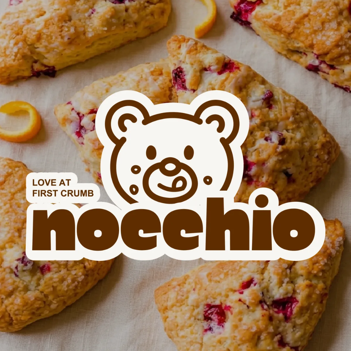 Nocchio Scone Shop logo, a bear licking its lips with crumbs on its face, over fresh scones