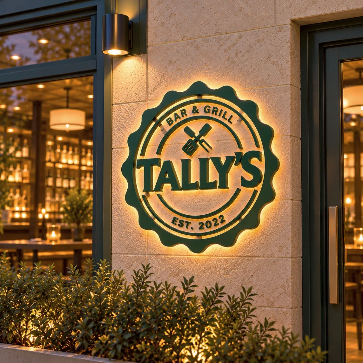 Tally's Bar & Grill logo as a backlit sign on a restaurant wall at dusk